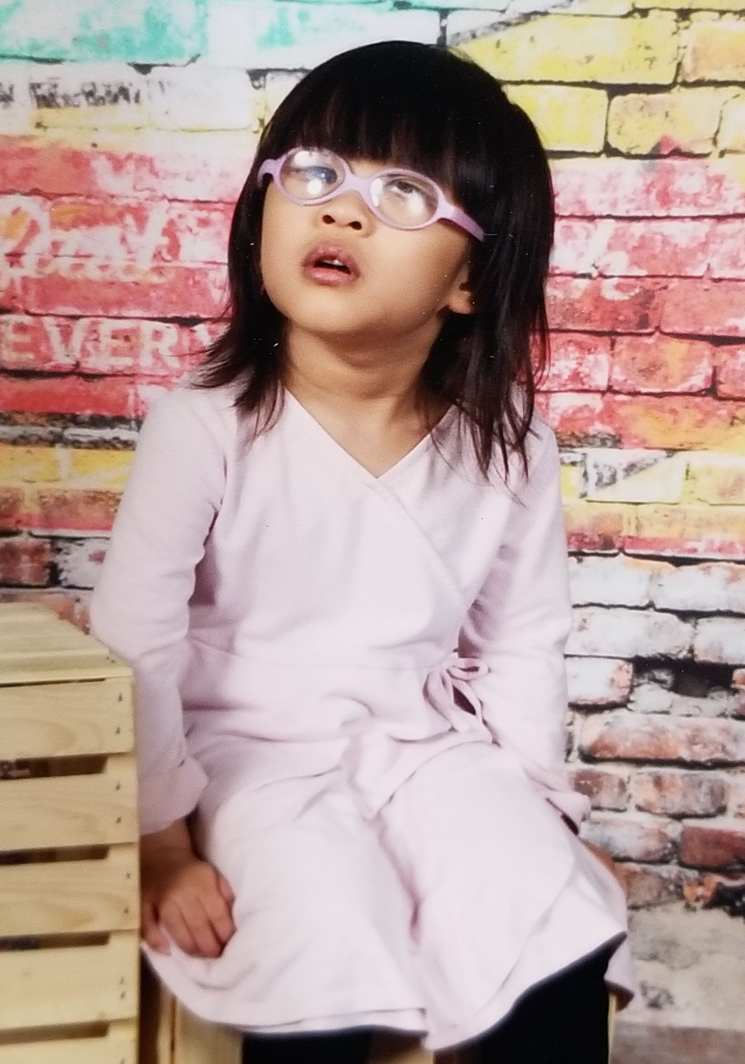 Clara pictured wearing a long sleeved pink dress and pink glasses