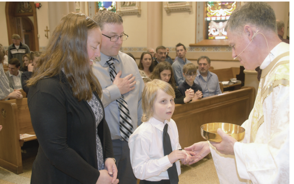 One of our patrons, a young boy, receives Holy Communion for the first time as his proud parents watch on