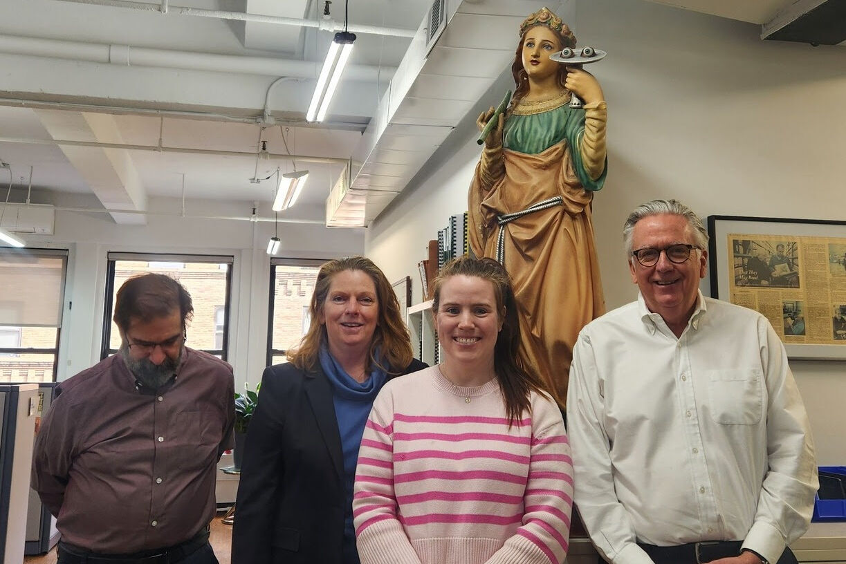 Donald, Aisling, and Malachy pictured with MaryBeth Wise from the National Library Service for the Blind and Print Disabled (NLS) in front of the St. Lucy statue in our office